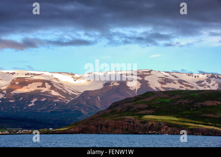 Le nord de l'Islande, Islande. 1er août 2015. Un règlement est situé sur les pentes de l'impressionnant des montagnes enneigées qui plongent dans les eaux d'¶EyjafjÃ rÃ°ur, le plus long fjord de nord de l'Islande. À côté de l'agriculture et de la pêche le tourisme est devenu un secteur en pleine croissance de l'économie et de l'Islande est devenue une destination touristique favorite. © Arnold Drapkin/ZUMA/Alamy Fil Live News Banque D'Images