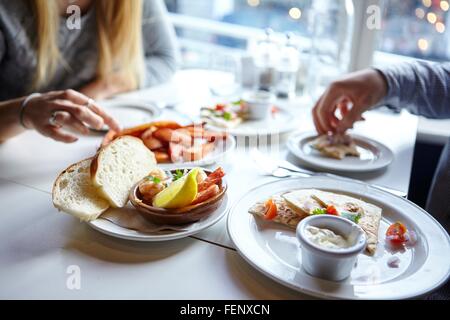 Cropped shot de jeunes couples mains manger finger food in cafe Banque D'Images