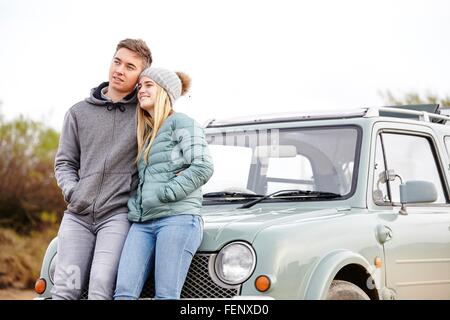 Jeune couple romantique appuyé contre voiture à beach Banque D'Images