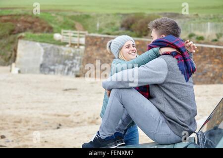 Couple assis sur un capot de voiture at beach Banque D'Images