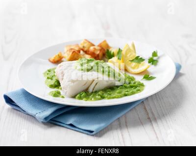 Filets d'aiglefin avec frites, sauce de pois à la menthe et de quartiers de citron Banque D'Images
