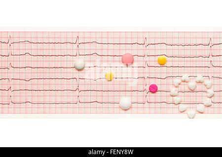 Coeur en forme de coeur blanc comprimés et blanc, jaune et comprimés roses sur papier les résultats de l'ECG isolé sur fond blanc Banque D'Images