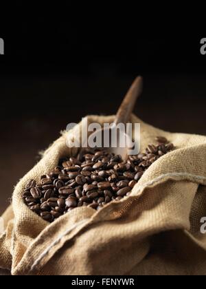 Les grains de café et écope en bois en sac tissé Banque D'Images