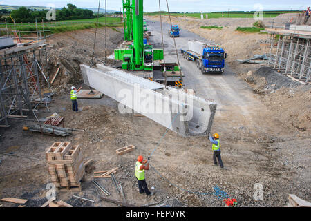 Les travailleurs de la construction sur la construction de l'infrastructure routière à l'aide de grue pour soulever les éléments préfabriqués en béton sur place Banque D'Images