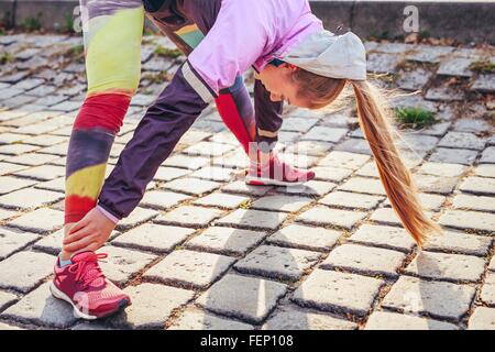 Mid adult female runner faire réchauffer l'exercice sur les pavés, Banque D'Images