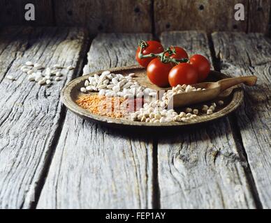 Portrait de lentilles rouges, beurre les fèves, les pois chiches, le safran et les tomates de vigne sur plaque de bois Banque D'Images