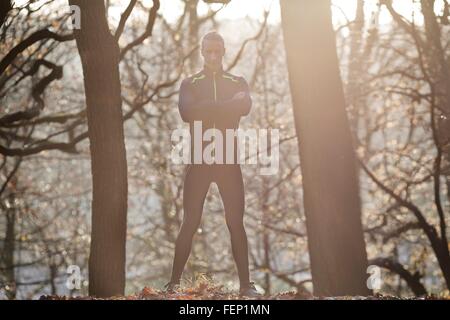 Vue avant pleine longueur de Mid adult man standing in forest arms folded looking at camera smiling Banque D'Images