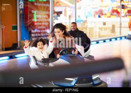 Mère et fille en auto tamponneuse bras levés smiling Banque D'Images