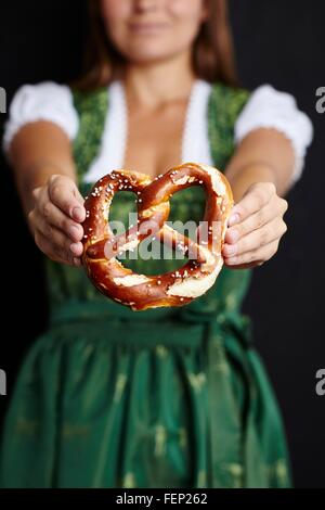 Jeune femme en Dirndl holding pretzel Banque D'Images