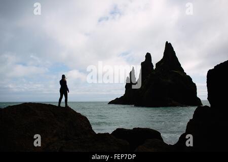 Silhouette of mid adult woman sitting on rock donnant sur l'océan, l'Islande Banque D'Images