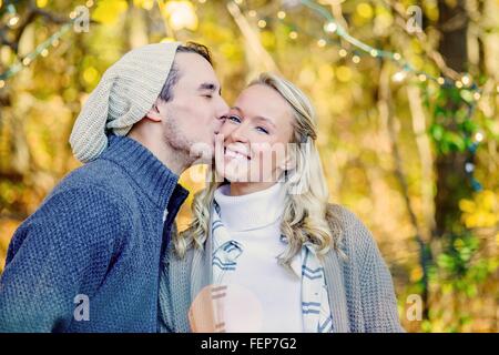 Portrait of young man kissing young woman on joue dans les bois Banque D'Images