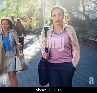 Jeune femme marchant à travers city park Banque D'Images