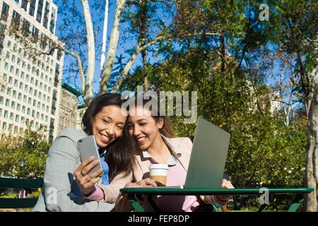 Les jeunes femmes adultes prenant des jumeaux en selfies smartphone city park Banque D'Images