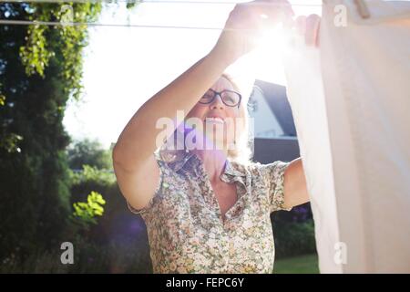 Senior woman hanging out washing in garden Banque D'Images