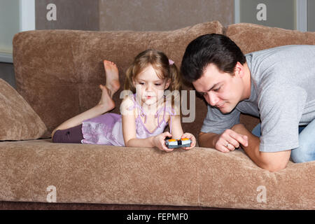 Petite fille à papa jouant sur le canapé Banque D'Images