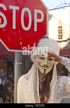 Asheville, Caroline du Nord, USA - 7 Février 2016 : femme portant un masque de Gut Fawkes symbolique de la rébellion est à côté d'un panneau d'arrêt et les saluts pendant un défilé de Mardi Gras le 7 février 2016 au centre-ville de Asheville, Caroline du Nord Crédit : Judith Bicking/Alamy Live News Banque D'Images