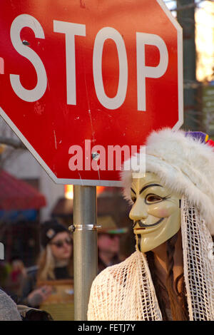 Asheville, Caroline du Nord, USA - 7 Février 2016 : femme portant un masque de Gut Fawkes symbolique de la rébellion est à côté d'un panneau d'arrêt au cours d'un défilé de Mardi Gras le 7 février 2016 au centre-ville de Asheville, Caroline du Nord Crédit : Judith Bicking/Alamy Live News Banque D'Images