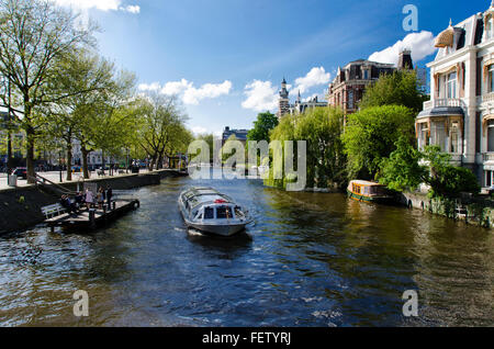 Amsterdam, Hollande, Canal - 7 mai 2016 : Bateau de tourisme navigation dans la carte, d'une part les bâtiments historiques, l'autre pas Banque D'Images