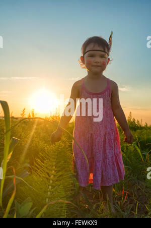 Funny little girl comme indien avec plumes et maracas Banque D'Images