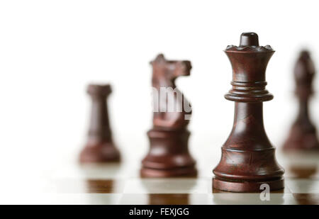 Image horizontale d'une partie d'échecs avec l'accent sur la reine et un flou des pièces de plus de fond blanc, copie de l'espace sur le côté gauche. Banque D'Images