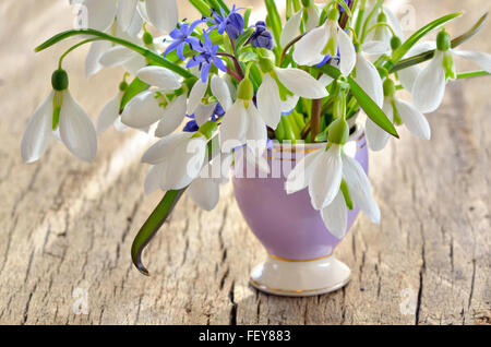 Bouquet de Crocus et perce-neige dans un vase en verre sur la vieille table en bois Banque D'Images