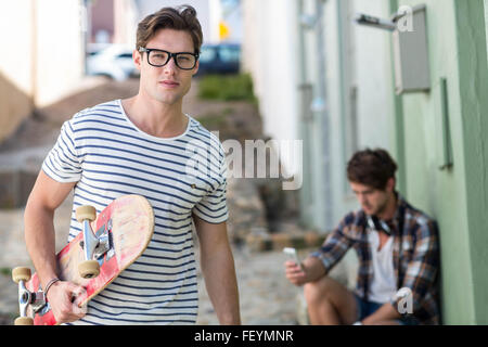 Hip man holding skateboard Banque D'Images