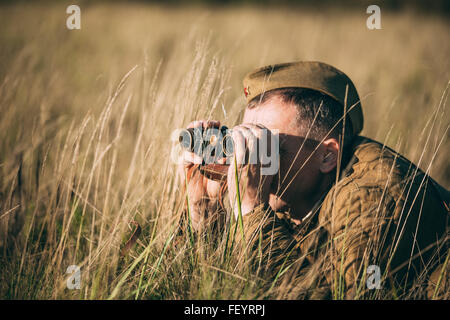 La reconstitution médiévale non identifiés habillés en soldat soviétique ressemble à une vieille armée de jumelles. Banque D'Images