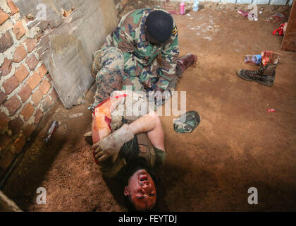 Maître de 2e classe Robert Otte, corpsman et instructeur-chef avec air-sol marin spécialisé crise Response-Africa Task Force, agit comme une victime comme une force de défense du peuple ougandais medic applique un garrot pendant un combat tactique théorique au Camp d'exercice Singo, Ouganda, 10 décembre 2015. L'UPDF medecins et corpsmen s'entraînent ensemble pour améliorer les soins médicaux tactiques des compétences tout en renforçant le lien entre les pays partenaires. Banque D'Images