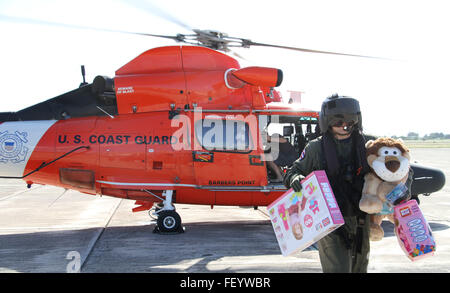 Maître de 1re classe Daryk Brekke, un technicien de maintenance de l'aviation de la Garde côtière à Air Station barbiers Point, déleste les jouets d'un hélicoptère MH-65 Dolphin à l'aéroport sur Oahu, Kalaeloa le 29 novembre 2015. Dans le cadre du programme Toys for Tots, gardes côte à partir de la gare de l'air recueillies Point barbiers jouets et dons qui vont être prises pour les membres du Corps des Marines et livrés aux enfants défavorisés pour Noël. Banque D'Images