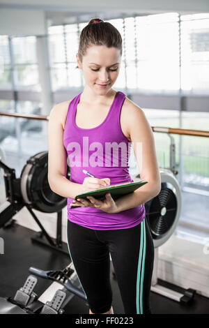 Joli trainer writing on clipboard Banque D'Images