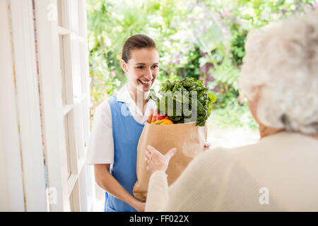 Belle infirmière portant des légumes aux ancien patient Banque D'Images