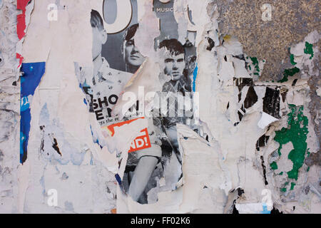 Visages de jeunes hommes sur l'épluchage des affiches sur un mur de la rue latérale du centre de Londres. Banque D'Images