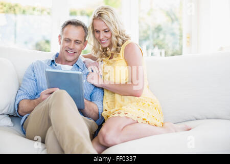 Couple heureux à l'aide de tablette sur le canapé Banque D'Images