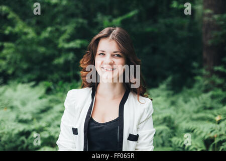 Close Up Portrait of a Smiling Young Happy Beauty Hair Girl rouge veste blanche en été dans la forêt du parc Banque D'Images