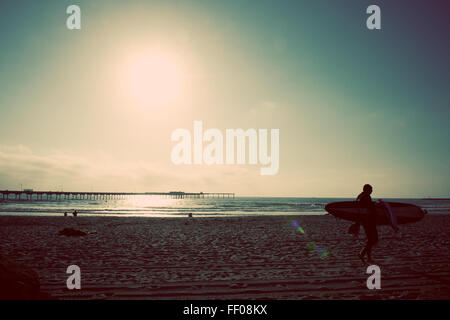 Un surfeur survole les vagues sur une plage de San Diego, en Californie, capturant l'essence de la culture du surf de la ville. La scène met en valeur le rivage, le soleil et l'activité de plein air vibrante du surf. Banque D'Images