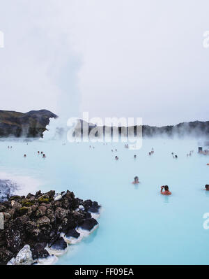 Un groupe de personnes se détend dans une source thermale géothermique, profitant des eaux chaudes thérapeutiques. La source riche en minéraux fait partie d'un environnement thermal naturel qui favorise le bien-être et la détente. Banque D'Images