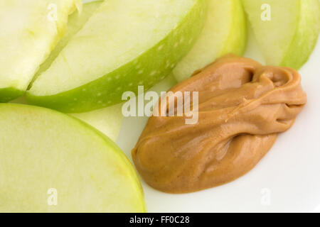 Fermer la vue d'un groupe de tranches de pomme verte sur un plat avec une petite quantité de beurre d'arachide pour tremper. Banque D'Images