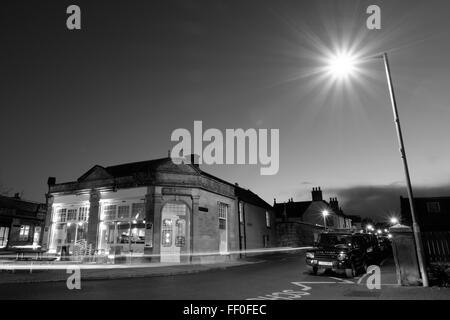 Une scène de nuit en noir et blanc de la salle de classe Restaurant avec une lumière de rue et de stries de voiture. Banque D'Images