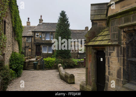 Les pavés, sur la rue de l'Église, Porte de St Michel et tous les Anges et de cottages en pierre - village de Haworth Bronte, West Yorkshire, GB, au Royaume-Uni. Banque D'Images