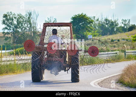 Tracteur avec un diviseur de foin sur la route Banque D'Images