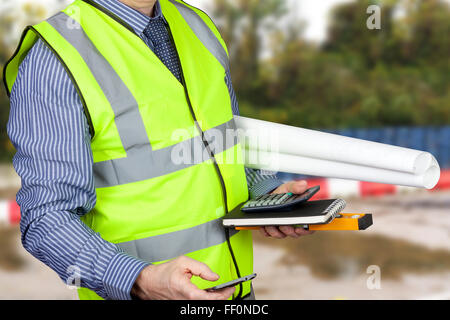 Building surveyor en hi vis l'exécution du plan de site et calculatrice et les plans du site Banque D'Images