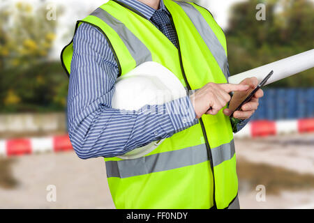 Building surveyor en hi vis gilet avec les plans du site vérifie son smart phone sur place Banque D'Images