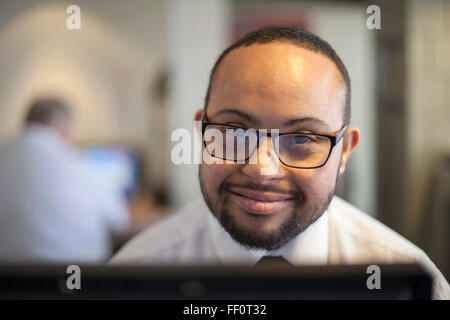 Mixed Race businessman with down syndrome working on computer Banque D'Images