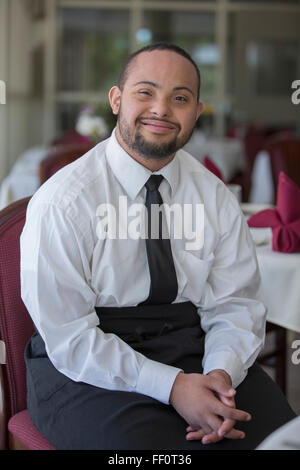 Mixed Race server avec syndrome de Down smiling in restaurant Banque D'Images