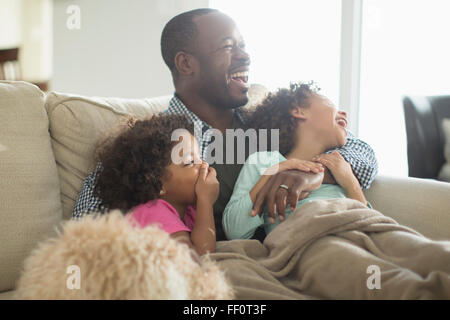 Père et filles à regarder la télévision sur le canapé Banque D'Images