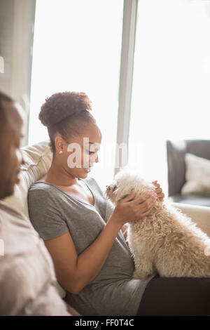 Couple petting dog on sofa Banque D'Images