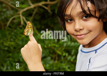 Mixed Race boy holding butterfly Banque D'Images