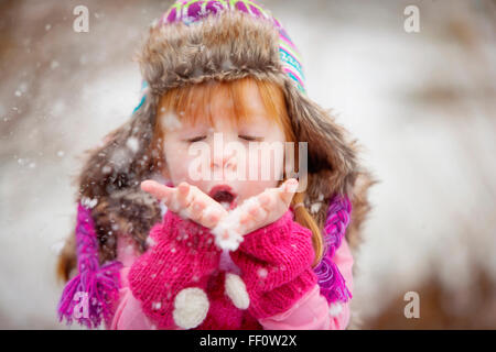 Young Girl blowing poignée de neige Banque D'Images