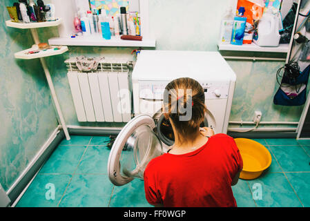 Caucasian woman chargement en blanchisserie sèche-linge Banque D'Images