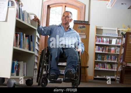 Caucasian man choisir book in library Banque D'Images